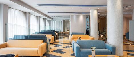 A hotel lobby with a checkered floor, multiple seating areas, and large columns.