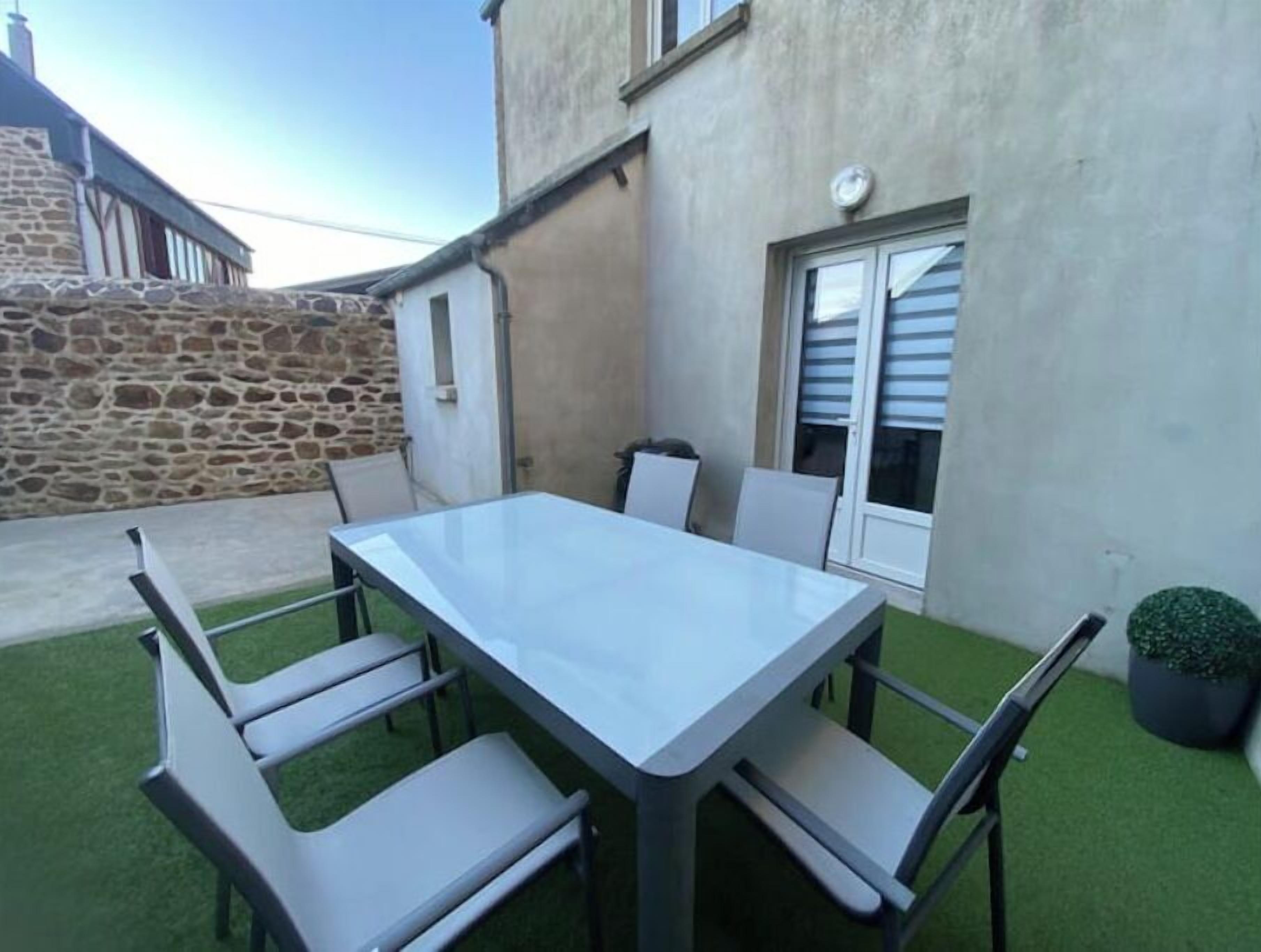 Un patio con una mesa rectangular y seis sillas.