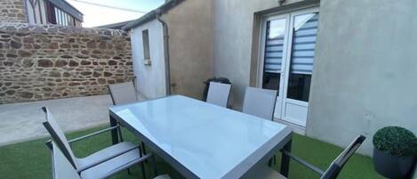 Un patio con una mesa rectangular y seis sillas.