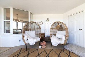 A room with two wicker chairs, a bench, and a small pumpkin decoration on the floor.