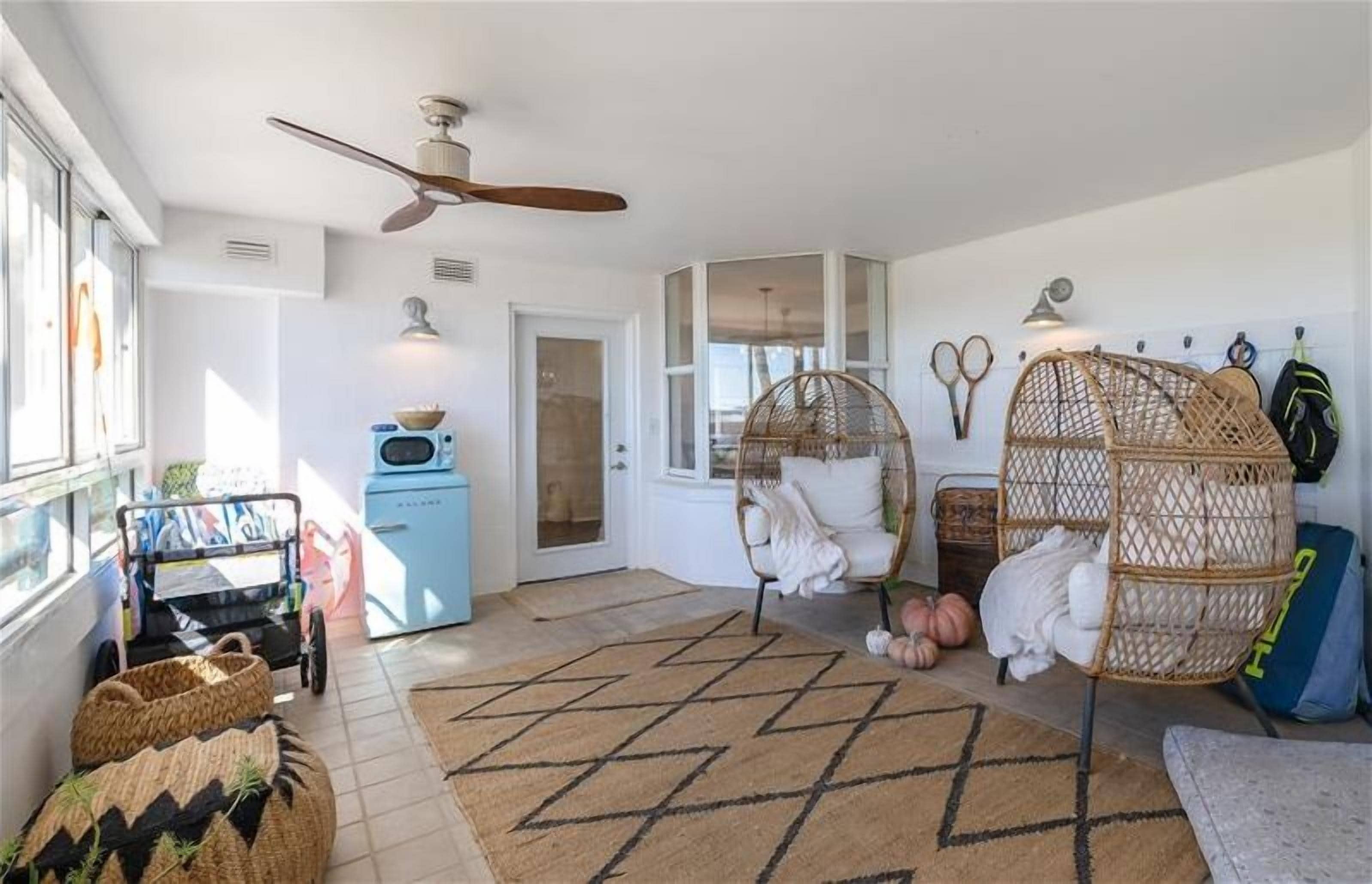A cozy living room with a rattan chair, a blue cabinet, and a woven basket.