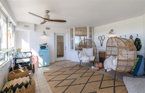 A cozy living room with a rattan chair, a blue cabinet, and a woven basket. - Luxury at its Finest - 3306 Towers - Traffic Free Beach - 3/3 Oceanfront (Ponce Inlet)