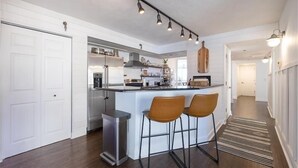 Een moderne keuken met een centraal eiland, barstoelen en hanglampen.