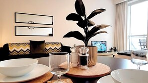 A modern living room with a sofa, a coffee table, a TV, and a large window.