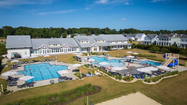 Un grand complexe hôtelier doté de plusieurs piscines, de chaises longues et d’une zone de plage.