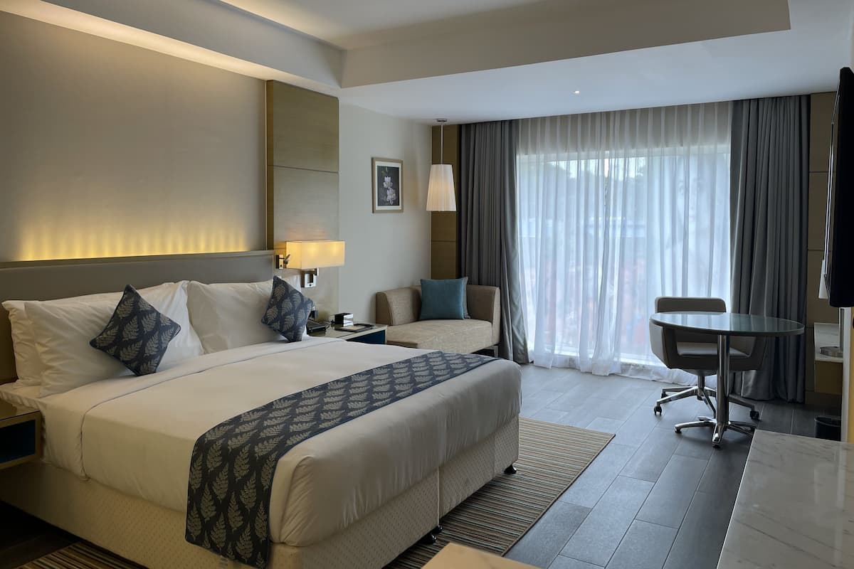 Ein Hotelzimmer mit einem großen Bett, einem Schreibtisch, einem Stuhl und einem Fernseher.