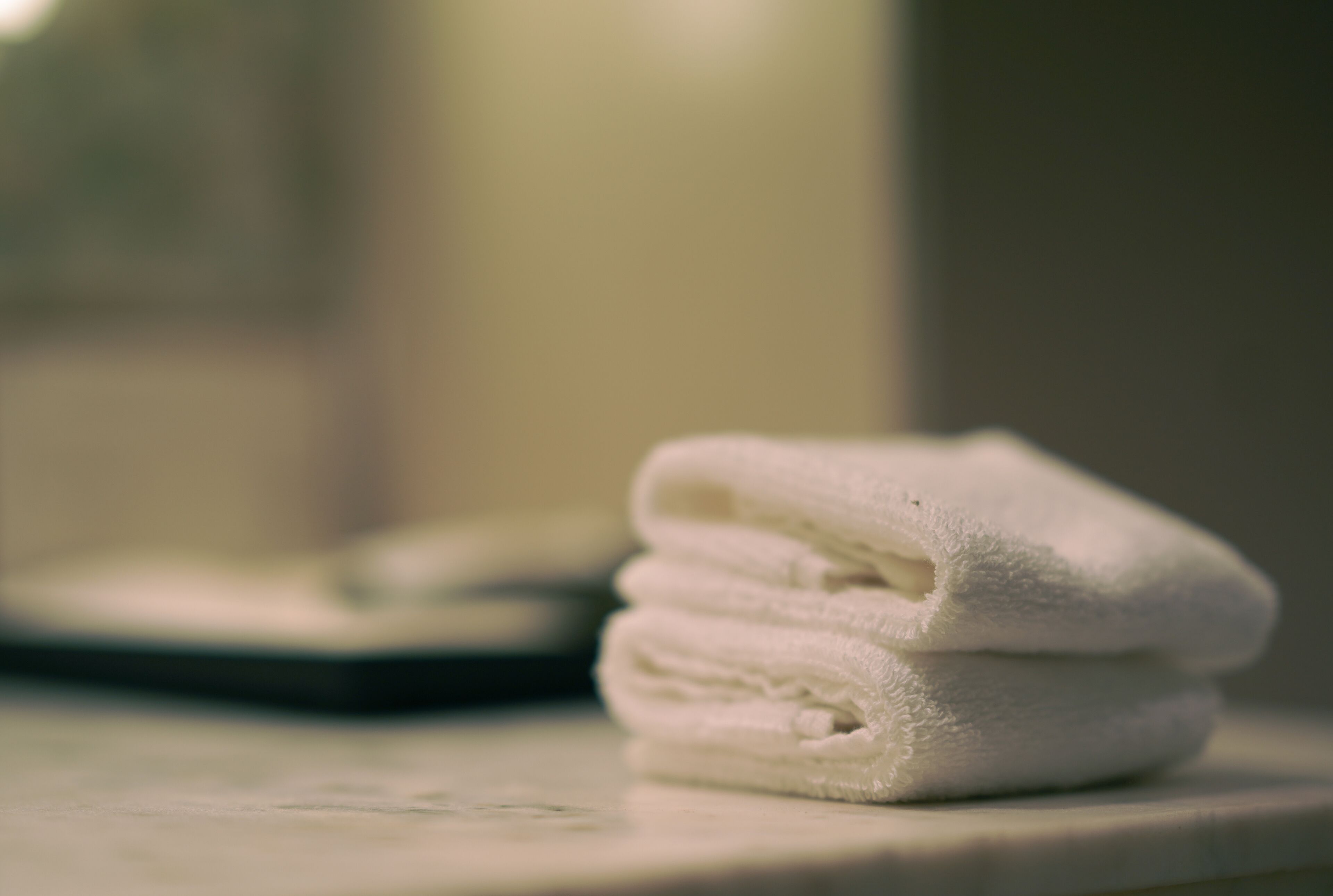 Une pile de serviettes blanches est posée sur le comptoir de la salle de bain.