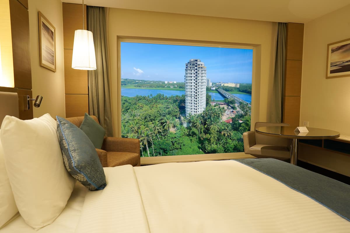 Ein Hotelzimmer mit einem großen Bett, Blick auf ein hohes Gebäude, einem Esstisch und einem Stuhl.