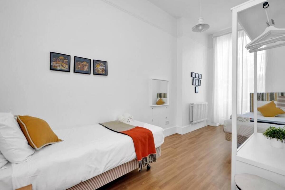 Un dormitorio moderno con cama, mesita de noche, espejo y un pequeño estante con adornos.