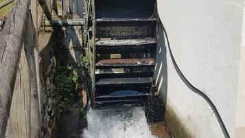 A water wheel with water flowing through it, connected to a wooden structure.