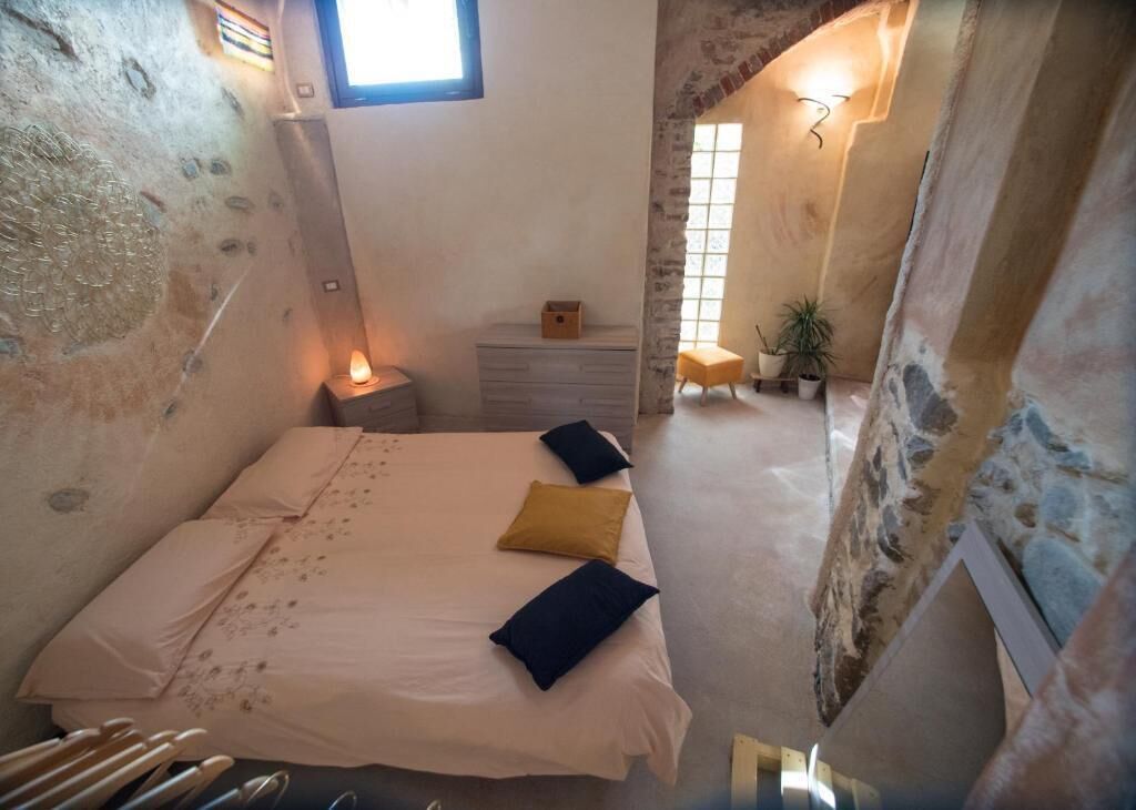 Un dormitorio con cama, mesita de noche y ventana.