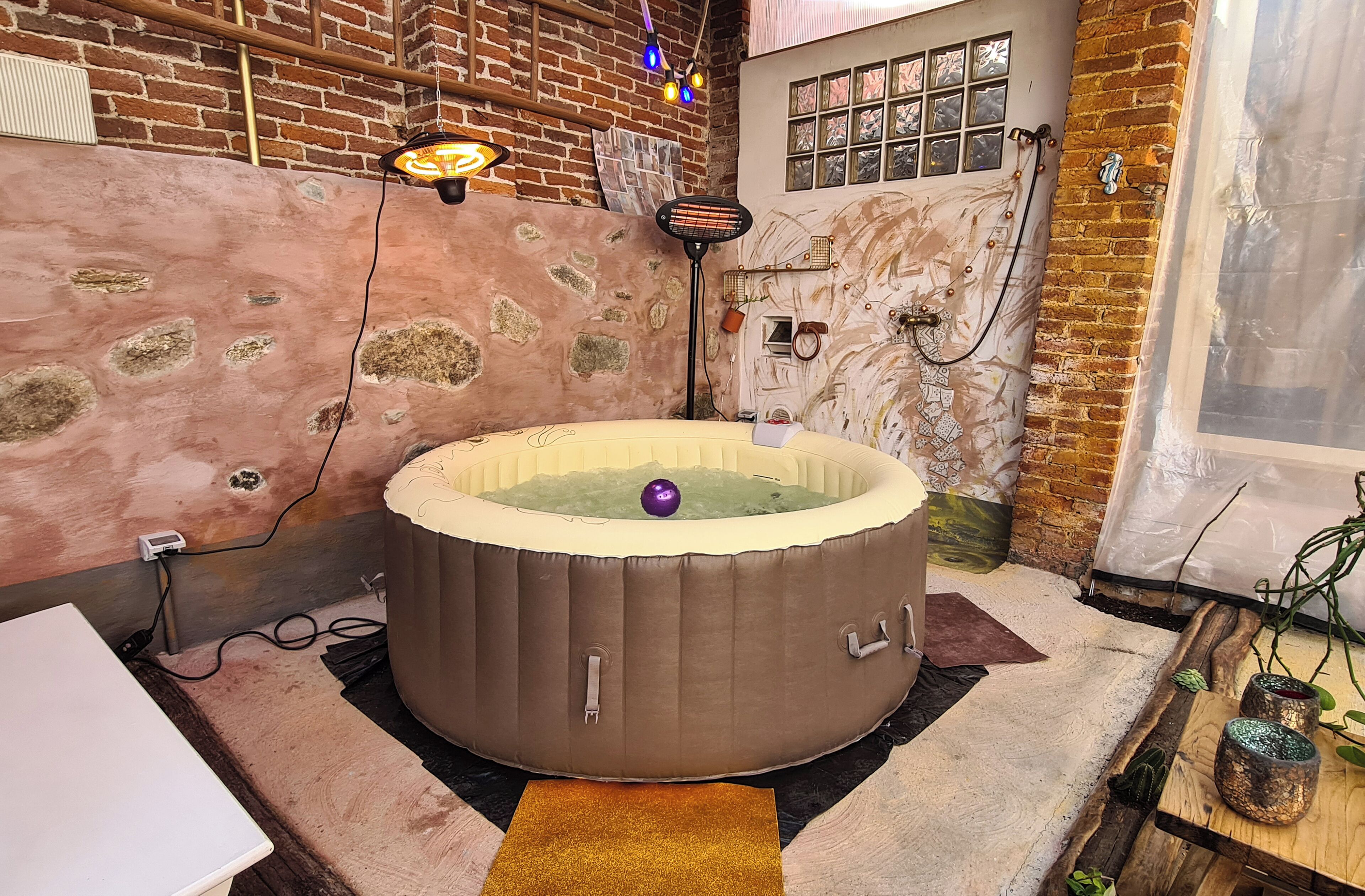 Una habitación con bañera de hidromasaje, paredes de ladrillo y un ventanal.
