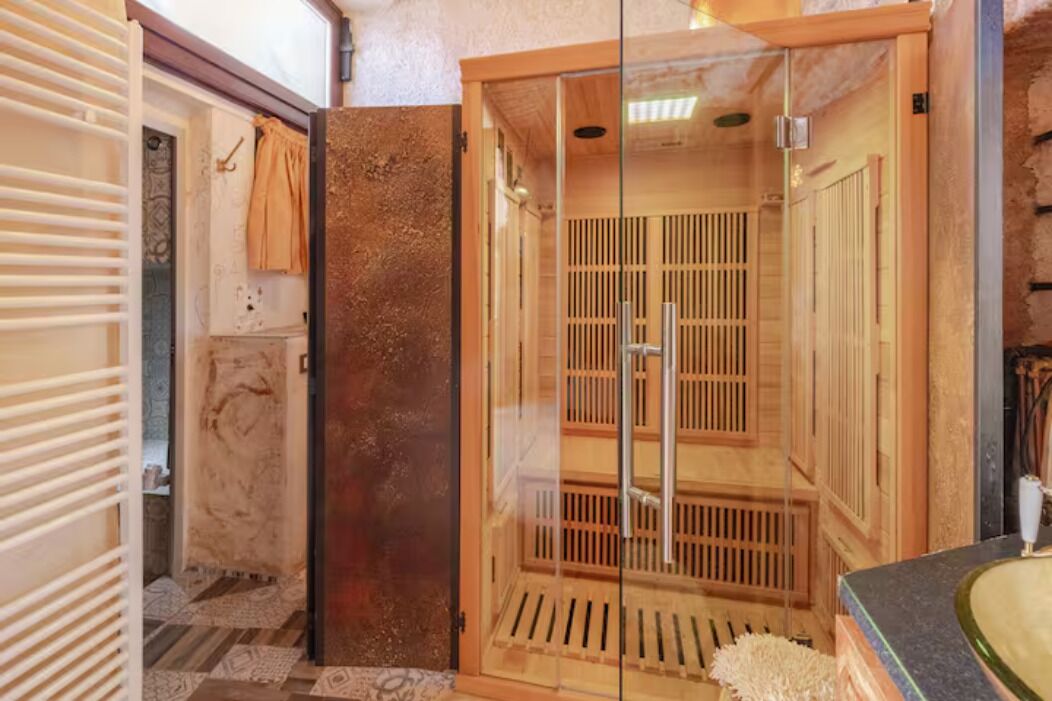 Una sauna con puerta de vidrio, bancos de madera y suelo de baldosas.