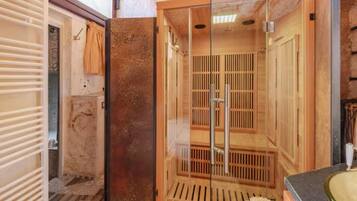 Una sauna con puerta de vidrio, bancos de madera y suelo de baldosas.