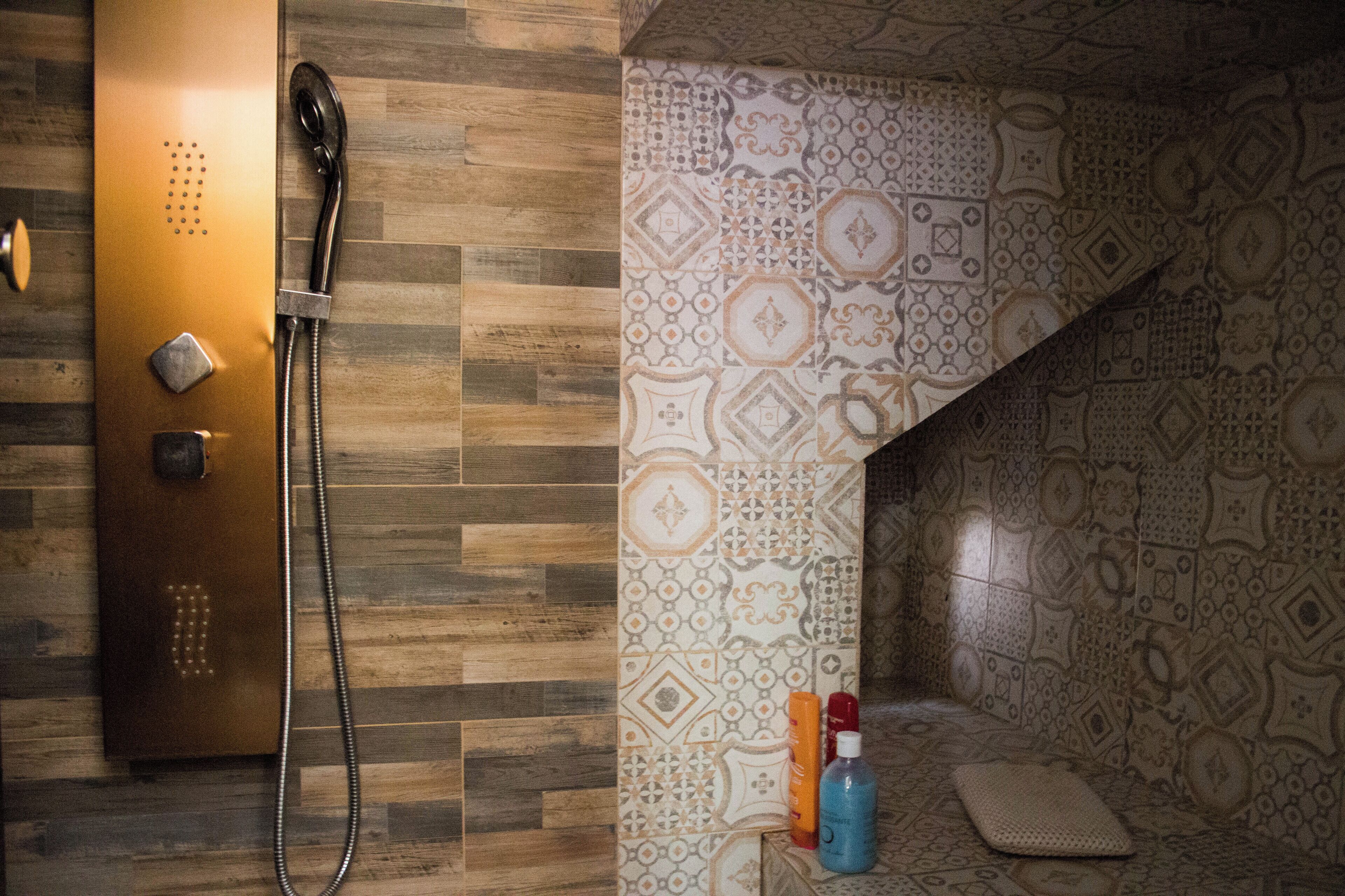 A bathroom with a wooden floor, patterned tiles, a shower, and a towel rack.