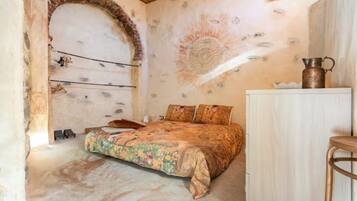 Un dormitorio con cama, un banco de madera, un armario y un mural decorativo en la pared.