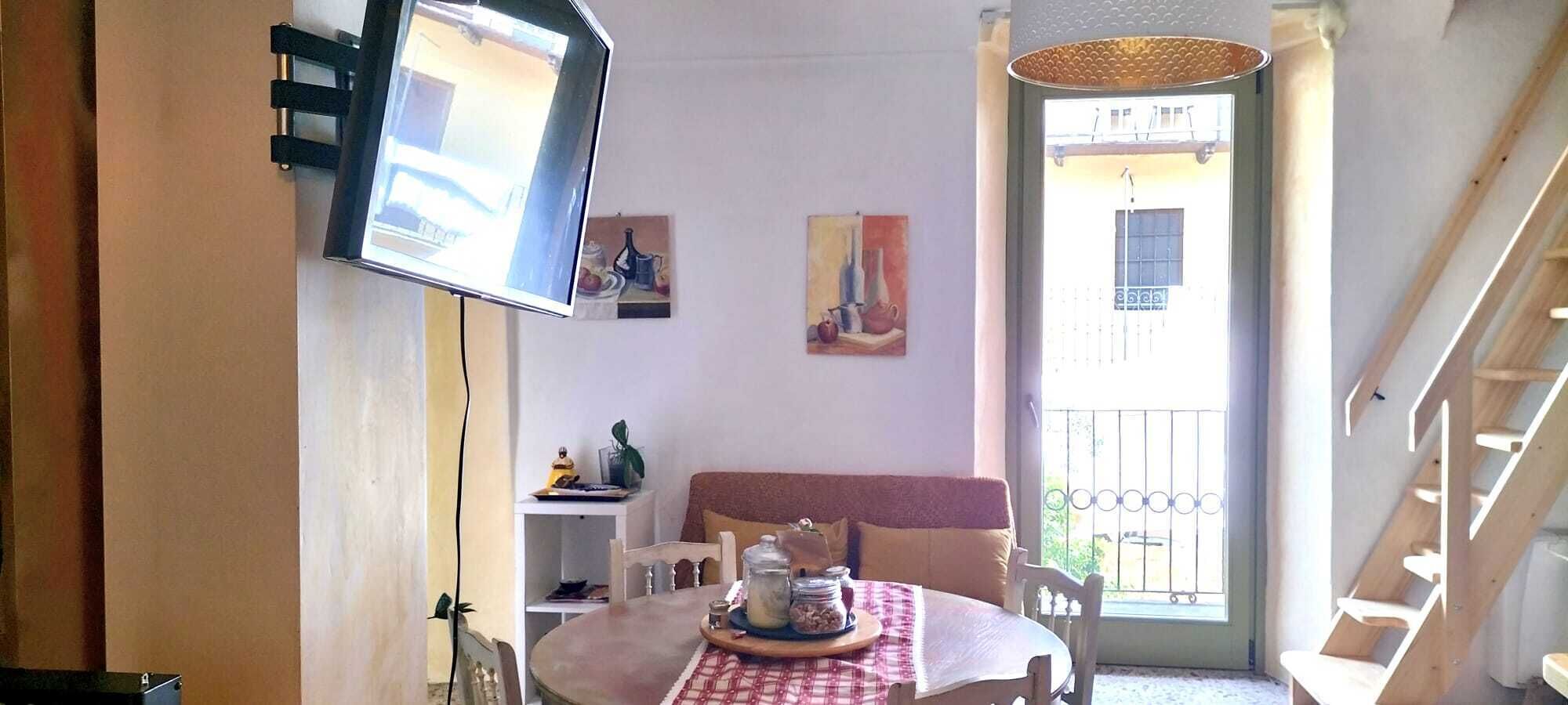 Ein gemütliches Wohnzimmer mit Esstisch, Sofa und Wandfernseher.