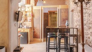 A rustic kitchen with a wooden table and bar stools, a brick wall, and a hanging light fixture. - CasaRosada Wellness Guest House (Vidracco)