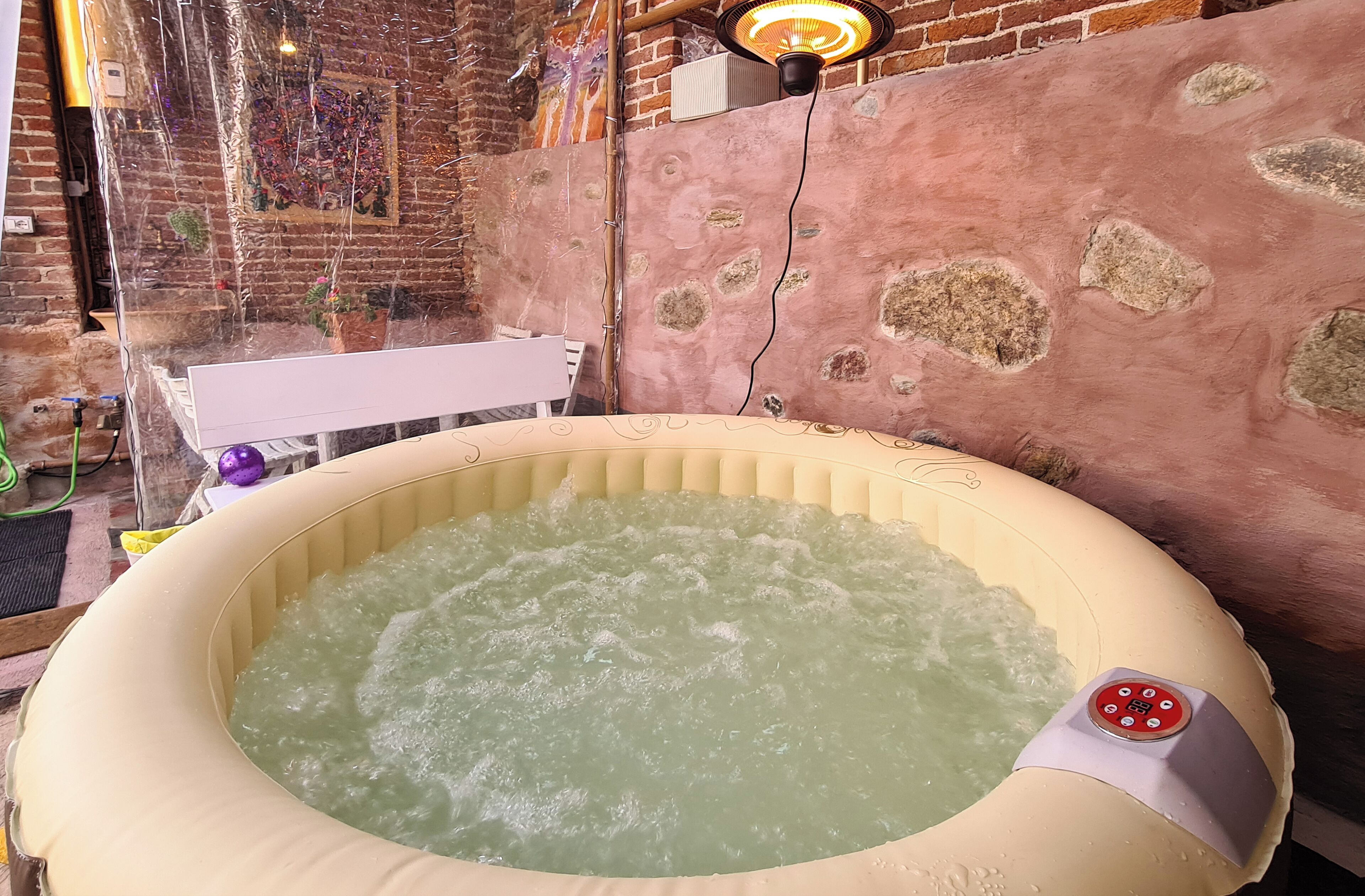 Un jacuzzi en una habitación rústica con pared de ladrillo y pared de piedra.
