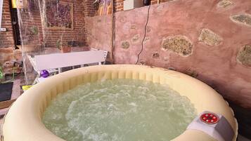 Un jacuzzi en una habitación rústica con pared de ladrillo y pared de piedra.