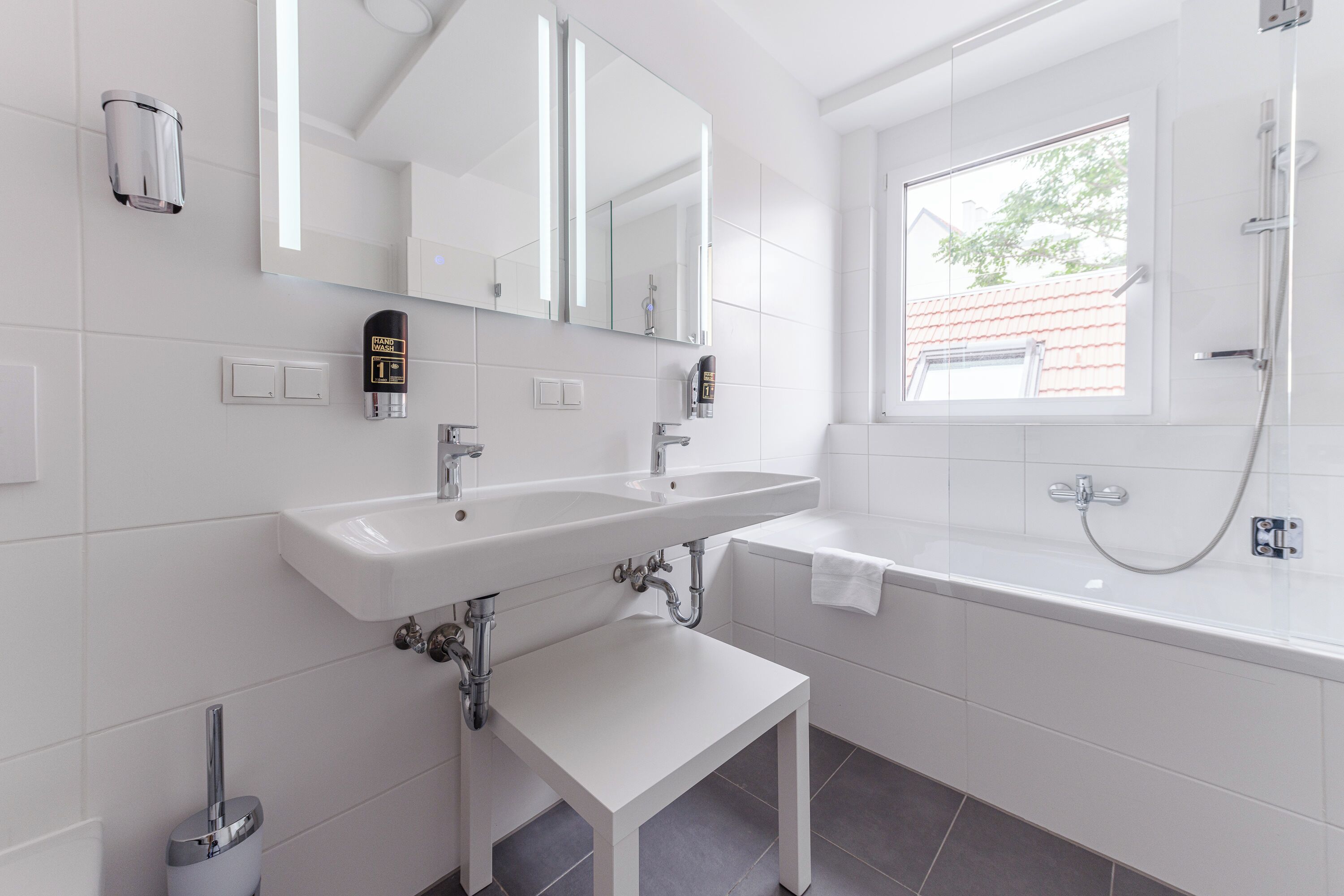 Een moderne badkamer met een wit wastafelmeubel, spiegel en bad.