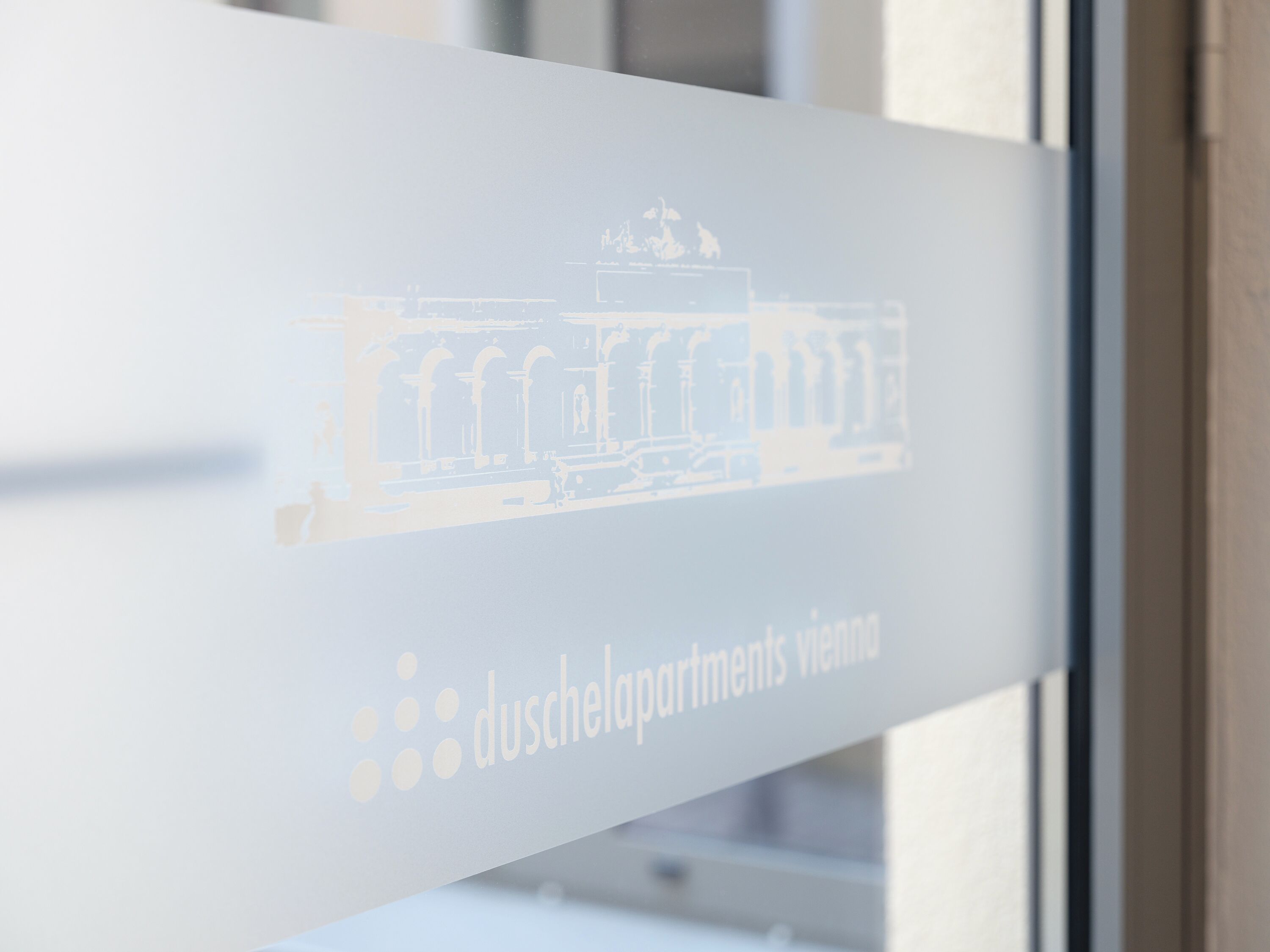 Une vitre avec un léger dessin architectural et l’inscription « duscheldomments Vienne ».
