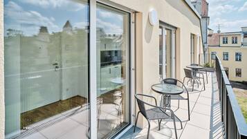 A modern balcony with glass doors, a small table, and two chairs.