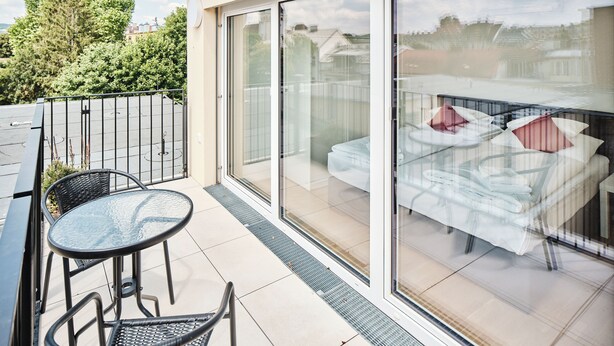 A balcony with a glass door, a table, and two chairs. - My Schönbrunn Apartments (Vienna)