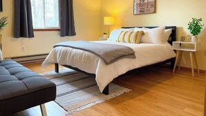 A bedroom with a bed, bedside table, lamp, and a painting on the wall. - Your Best Vacation is waiting at the Sage Chalet - Close to Kalahari & Camelback (Long Pond)
