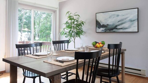 A dining area with a wooden table, black chairs, a potted plant, and a framed artwork on the wall. - Your Best Vacation is waiting at the Sage Chalet - Close to Kalahari & Camelback (Long Pond)