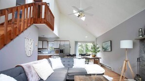 A modern living room with a grey sofa, wooden staircase, and a ceiling fan. - Your Best Vacation is waiting at the Sage Chalet - Close to Kalahari & Camelback (Long Pond)