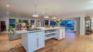 A spacious kitchen with a central island, pendant lighting, and a view of the outdoors. - Tropical beachfront villa in Umdloti - Endless summers (eMdloti)