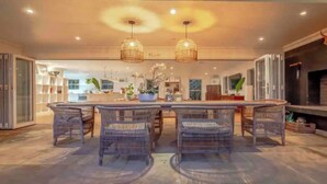 A spacious kitchen with a central island, wicker chairs, pendant lighting, and a brick fireplace. - Tropical beachfront villa in Umdloti - Endless summers (eMdloti)