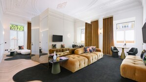 A modern living room with a large sectional sofa, a flat-screen TV, and a glass partition. - Montebelo Vista Alegre Lisboa Chiado, member of Preferred Hotels & Resorts (Lisbon)