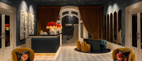 Eine luxuriöse Lobby mit Schachbrettmuster-Boden, einer zentral gelegenen Bar und Sitzgelegenheiten mit floralen Kissen.