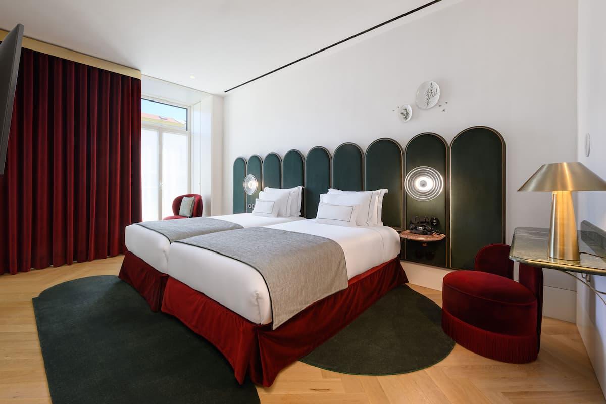 Une chambre d’hôtel moderne avec un grand lit, un bureau et une chaise rouge.