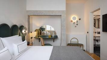 A modern hotel room with a large bed, a desk with a mirror, and a TV mounted on the wall.