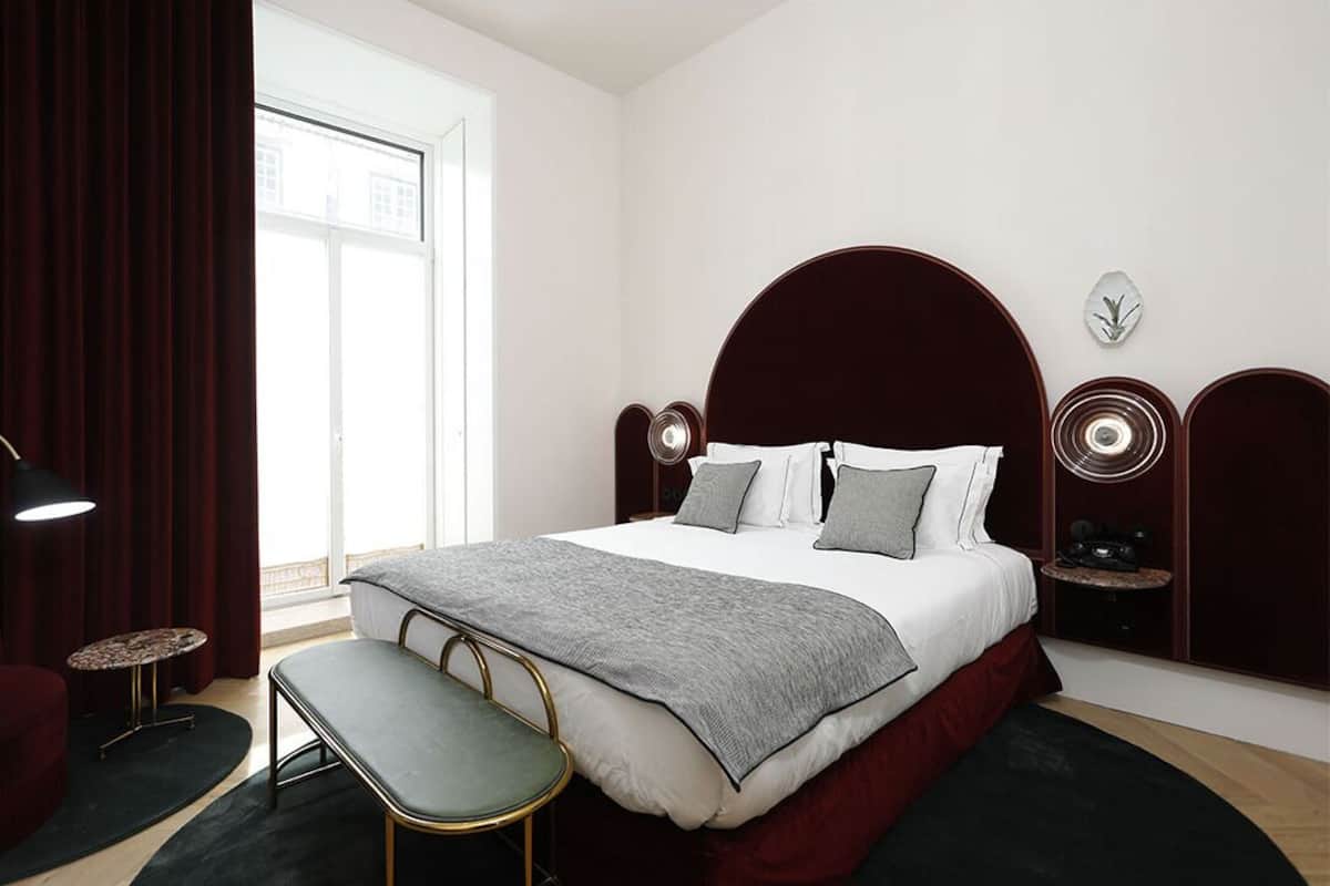 Une chambre moderne avec un grand lit, des tables de chevet, un banc et une fenêtre.