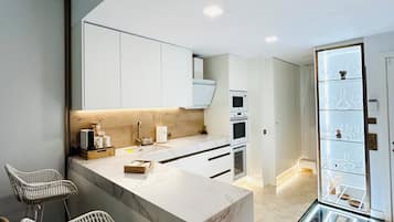 A modern kitchen with white cabinetry, a marble countertop, and a built-in wine rack.