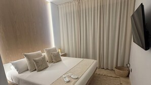 Un dormitorio moderno con una cama grande, un televisor de pantalla plana, una alfombra tejida y un cabecero de madera.