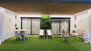 A patio with artificial grass, a round table with chairs, and two lounge chairs. - Apartamento Zen Garden. Valle del Este Golf (AN)