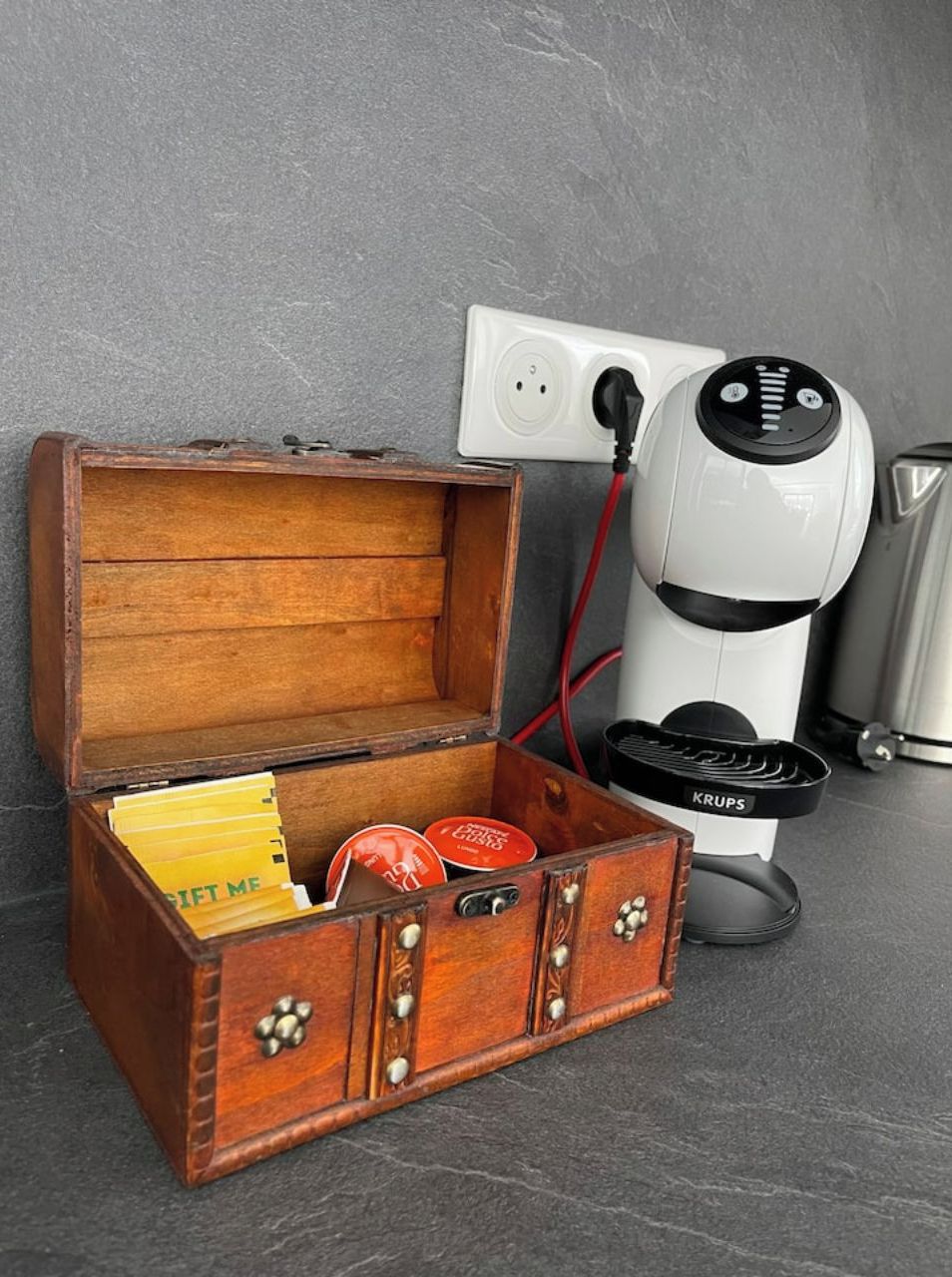 A wooden chest with a red cord plugged into a white power outlet.