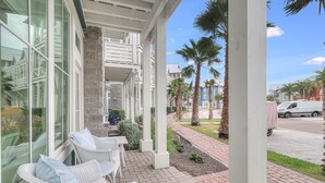 A covered outdoor seating area with wicker chairs and a stone wall.