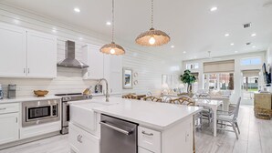 A modern kitchen with white cabinetry, stainless steel appliances, and a central island with seating.