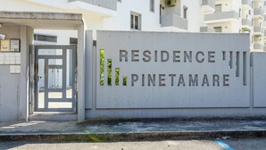 A gated entrance to a residential building named "Residence III Pinetamare" with a modern architectural style and multiple balconies.