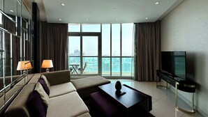 Un salon moderne avec un canapé, une table basse, un téléviseur et un balcon offrant une vue sur la ville.