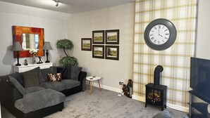 A living room with a sofa set, a small round table, a fireplace, and framed pictures on the wall. - The Sandgate New Immaculate 1-bed Apartment in Ayr (Ayr)