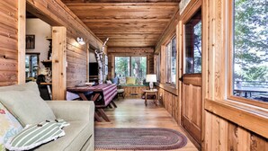 A cozy cabin interior with a sofa, a dining table, and a TV. - Stepaway Vacation Rentals - Shimmering Waters (St. Germain)