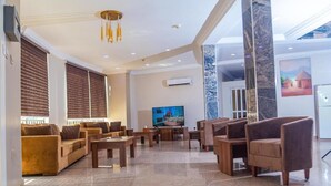 A spacious lobby with a large flat-screen TV, comfortable seating, and a marble column. - Guest Pride Hotel Kano  (Kano)