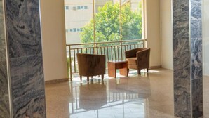 A spacious balcony with a view of trees and buildings, featuring two wooden chairs and a small table. - Guest Pride Hotel Kano  (Kano)
